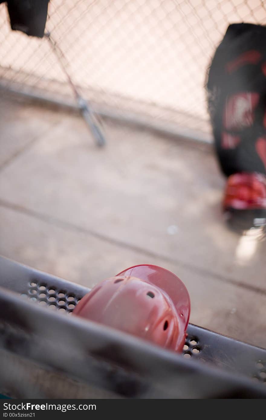 Baseball helmet and bats sitting outside on a bench against the bench during a baseball game