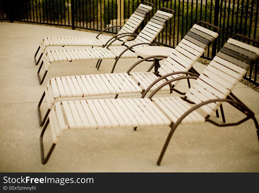 A group of four pool chairs next to each other outside during the summer time