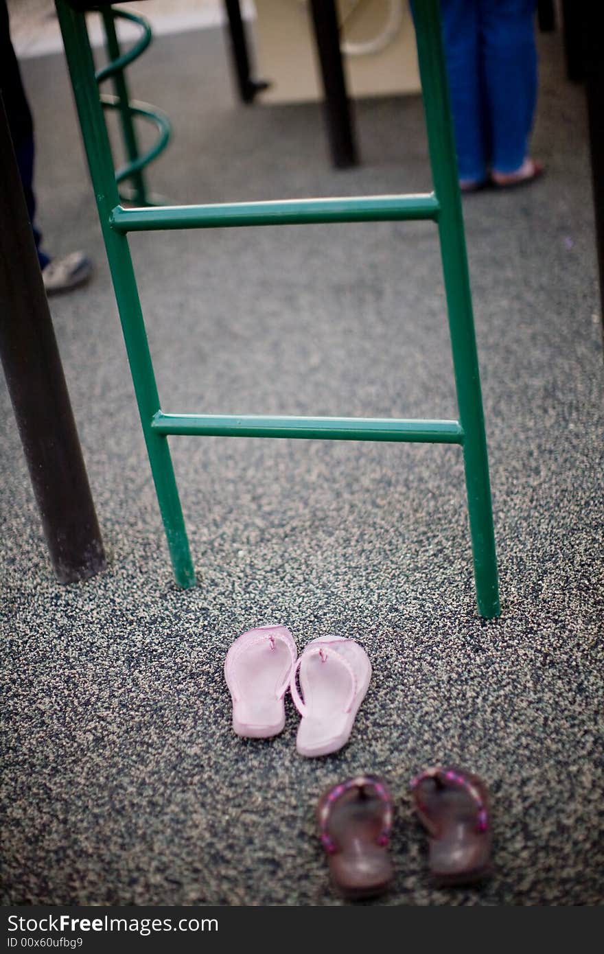 Shoes are resting in front of the playground where kids play outside. Shoes are resting in front of the playground where kids play outside