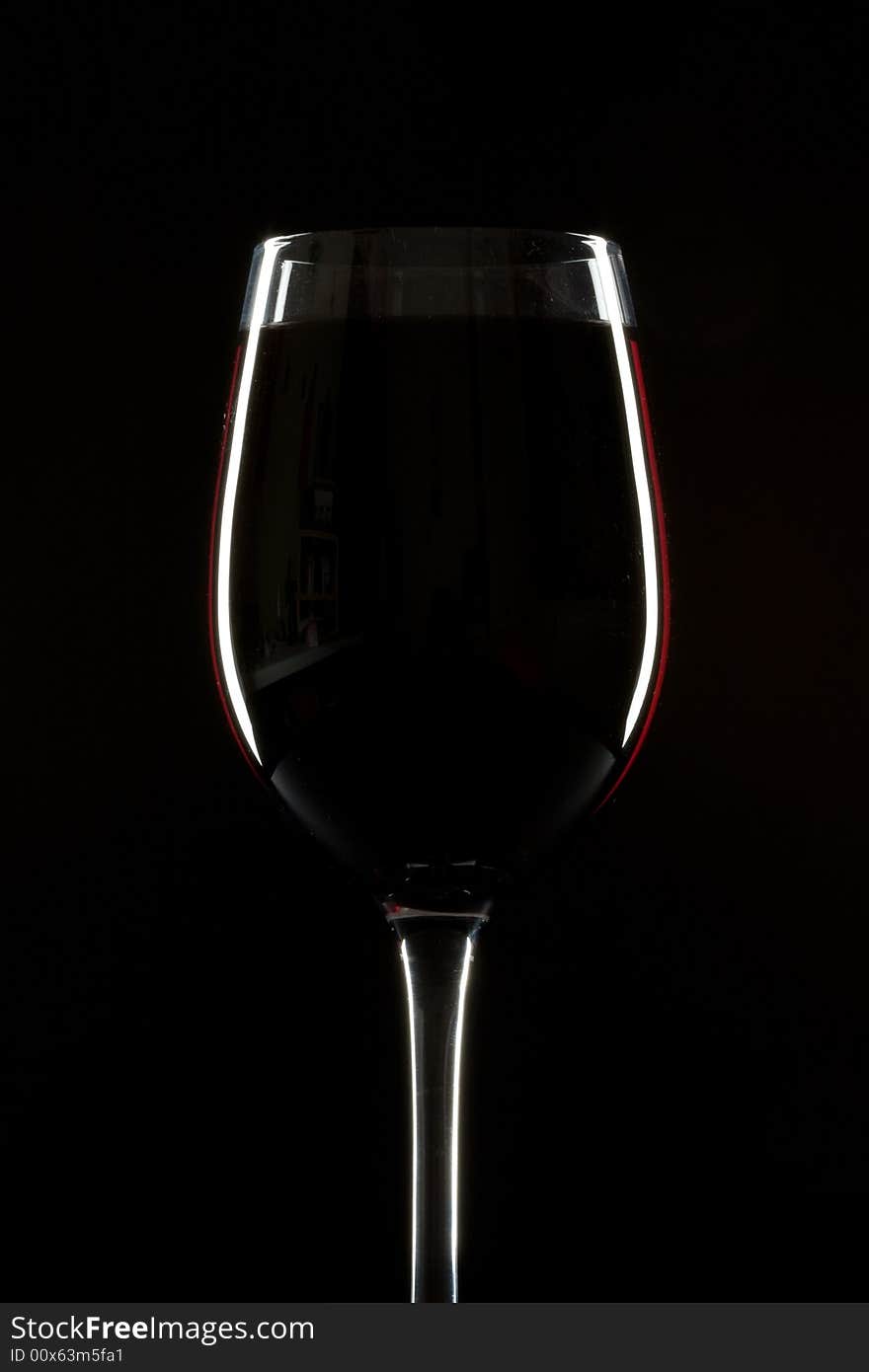 Red wineglass on a black background with rim light. Red wineglass on a black background with rim light