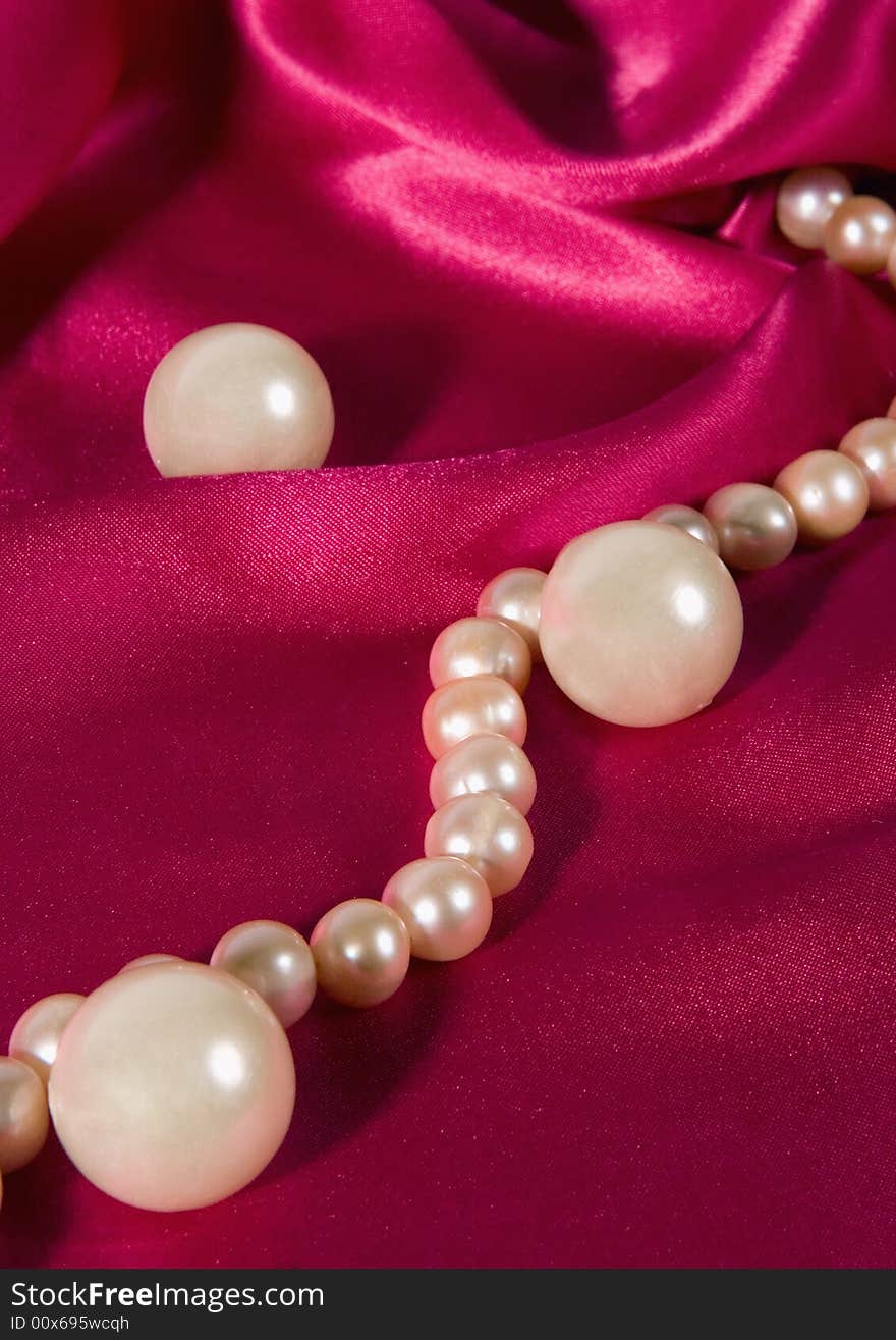 Pink pearl necklace on a violet silk.