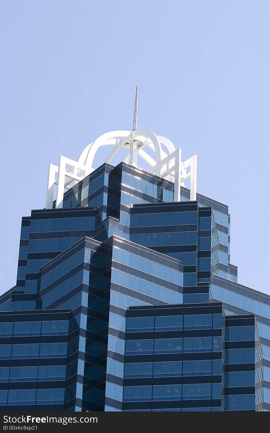 Top of a modern blue glass office tower against blue sky. Top of a modern blue glass office tower against blue sky