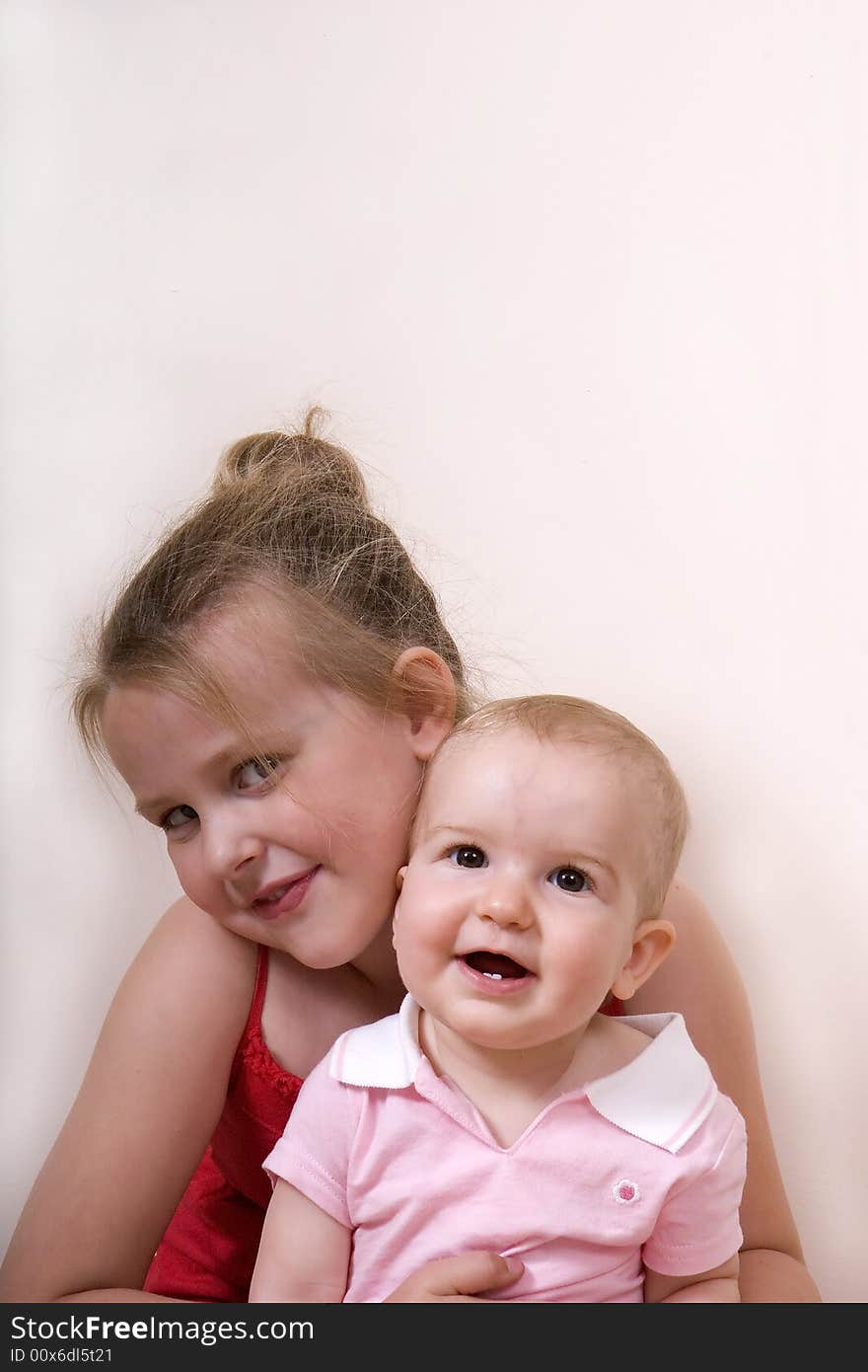 A young girl in a red dress and a baby in pink. A young girl in a red dress and a baby in pink