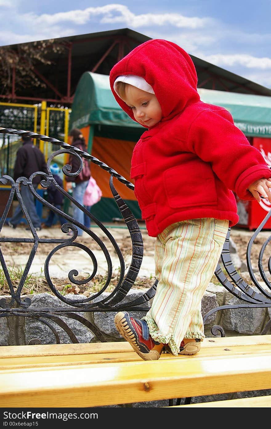 The little girl costs on a bench in the park. The little girl costs on a bench in the park