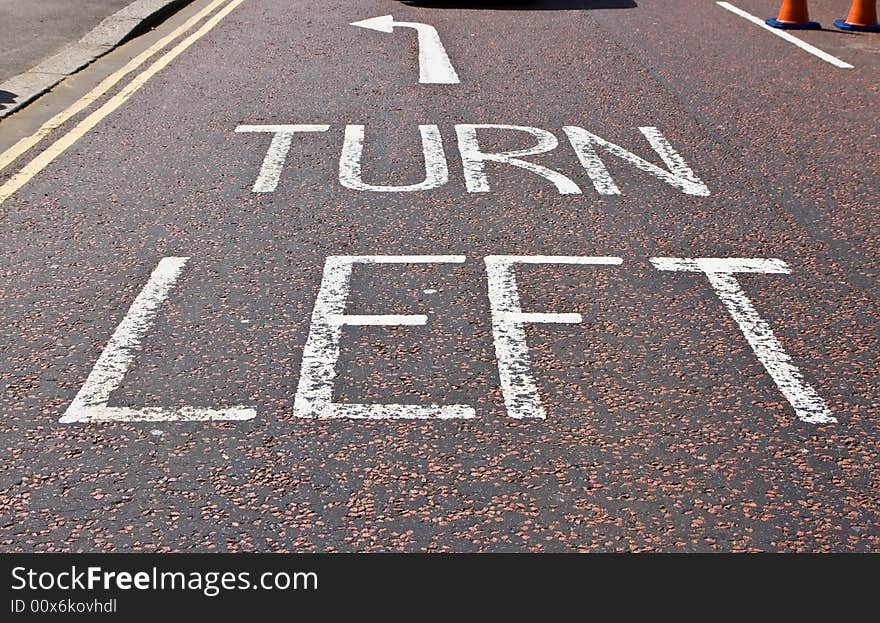 Turn left sign in typical London street asphalt