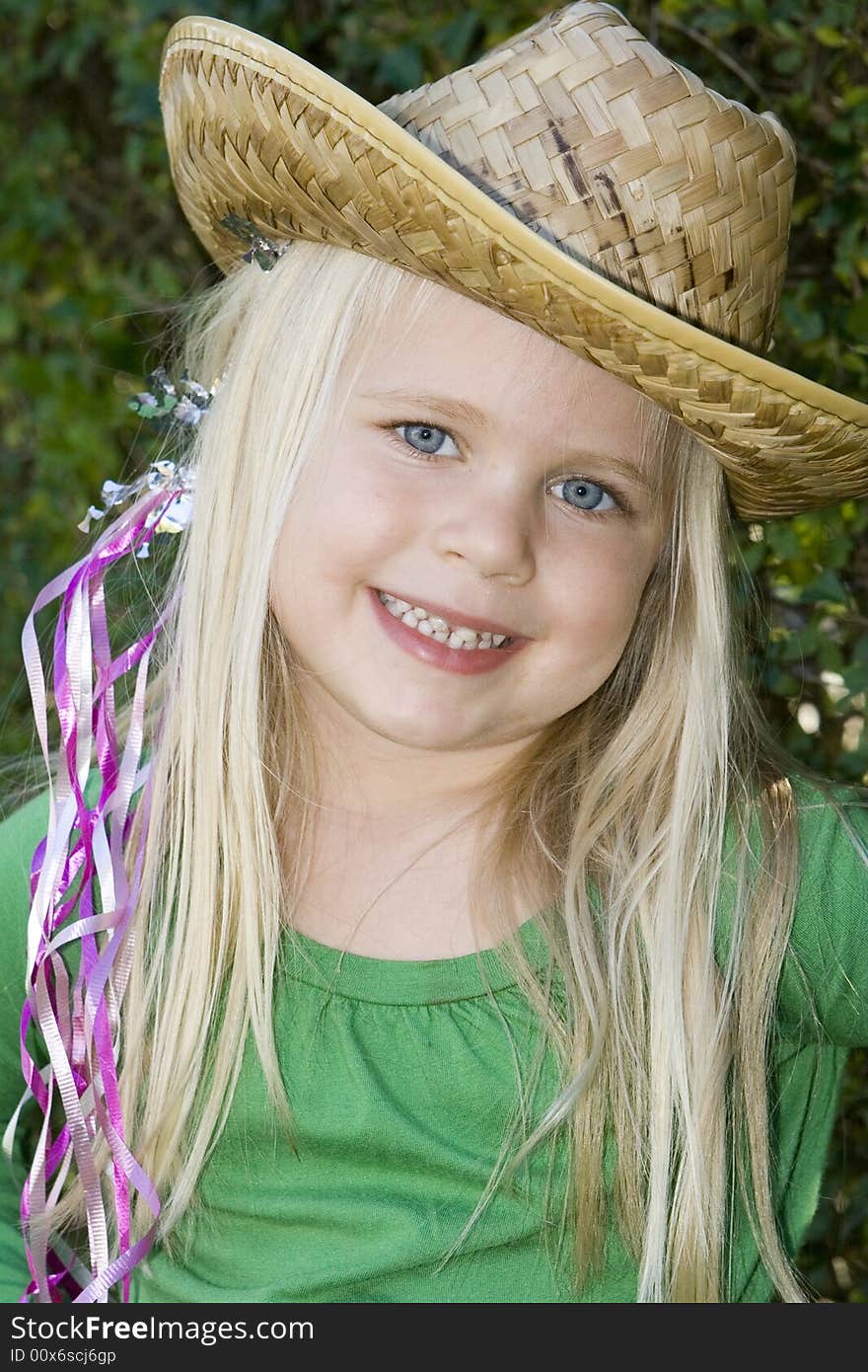 A little girl in a hat and green t-shirt with ribbons in her hair