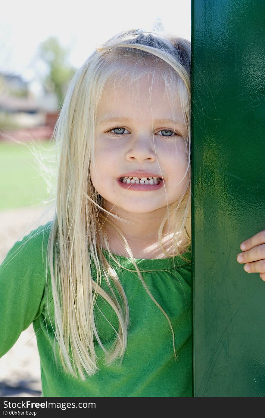 A little girl in a green t-shirt with long blonde hair