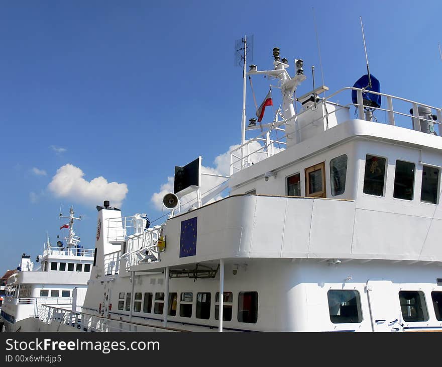 Two white passenger boats with control rooms located on the top. Two white passenger boats with control rooms located on the top.