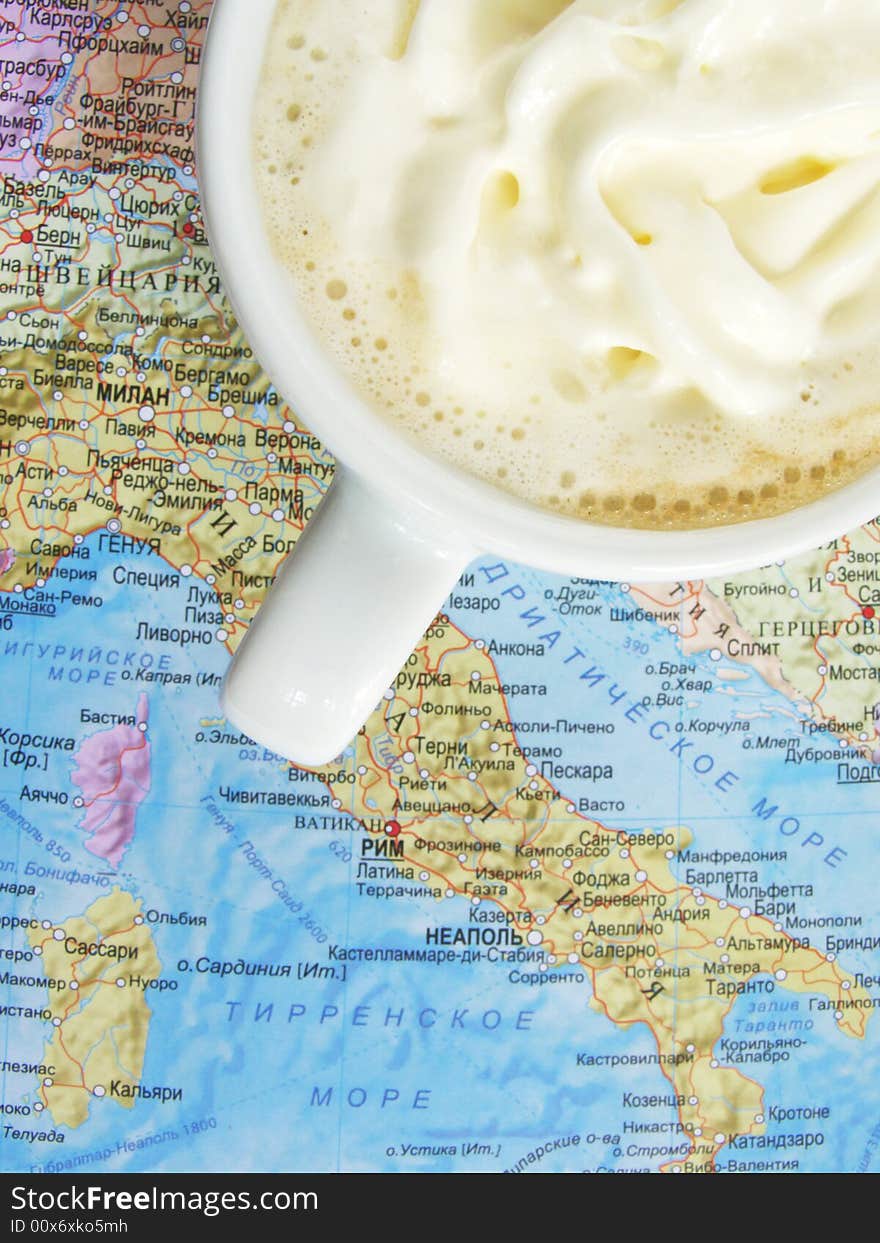 Cup of coffee with milk. Worth on the map. The map depicted Italy.