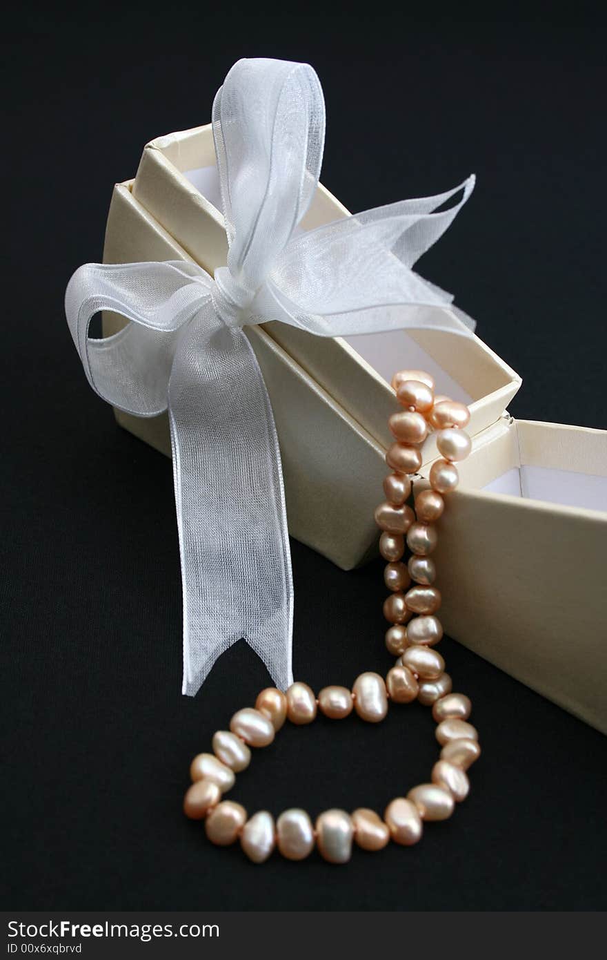 Small cream colored box with ribbon and pearl necklace