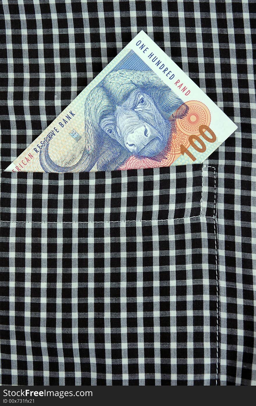 South African Rand banknote in the pocket of a casual garment.  Photographed in a studio.