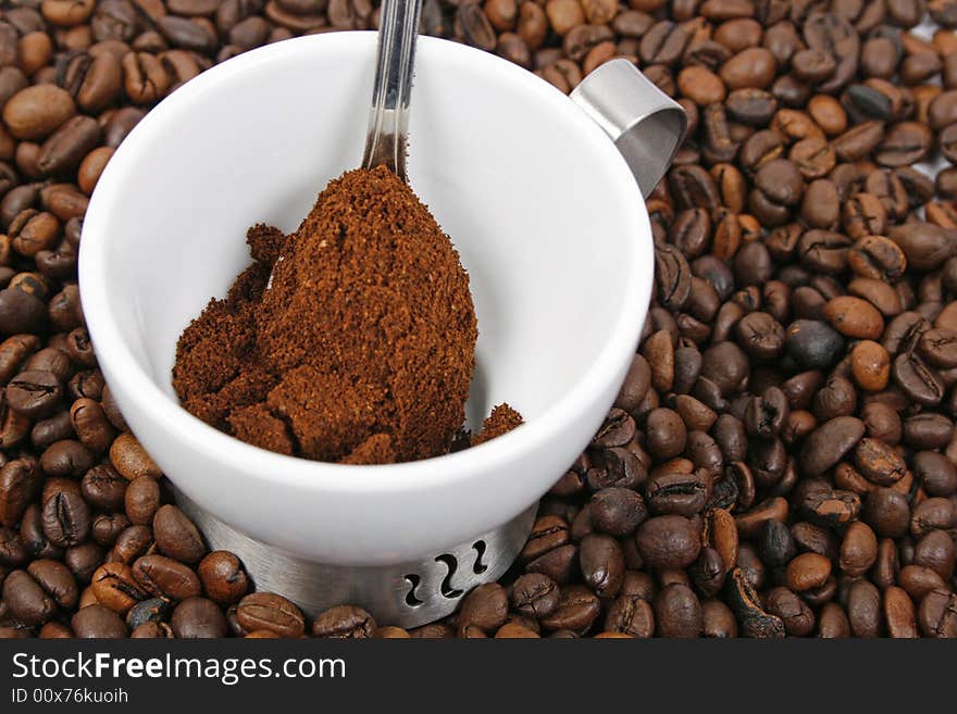 Coffee, spoon and white cup on coffee beans background. Coffee, spoon and white cup on coffee beans background