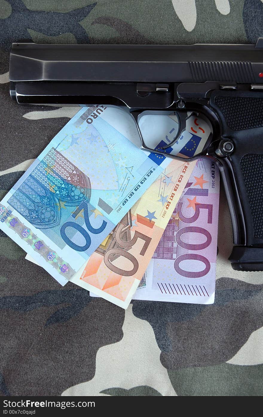 A pistol with an amount of Euros included in the photo.  Photographed in a studio.