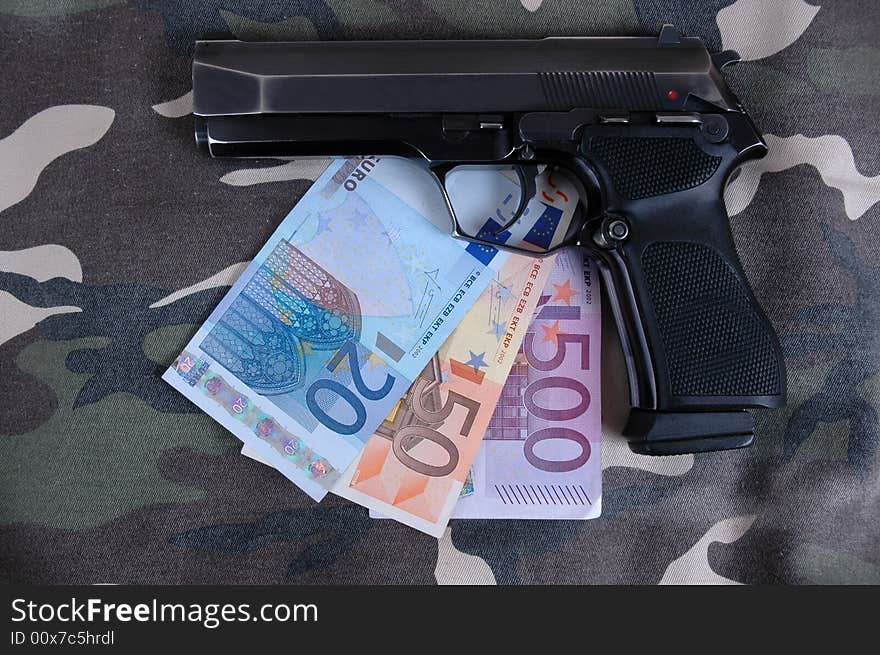 A pistol with an amount of Euros included in the photo.  Photographed in a studio.