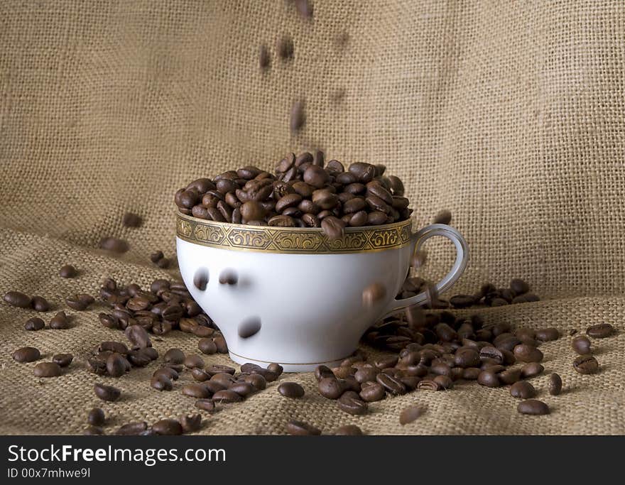 Beans falling into a little coffee cup. Beans falling into a little coffee cup