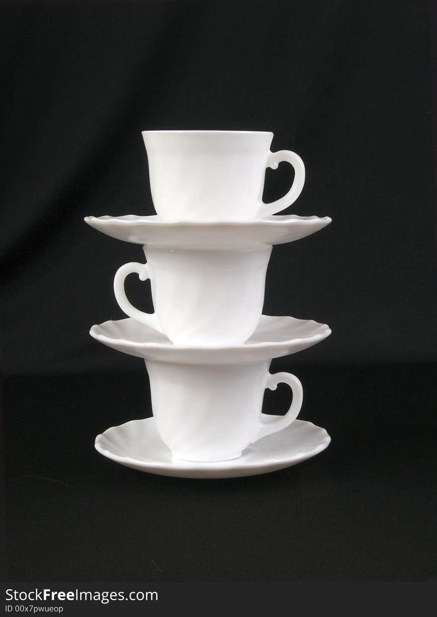 A stack of cups and saucers on the black background. A stack of cups and saucers on the black background