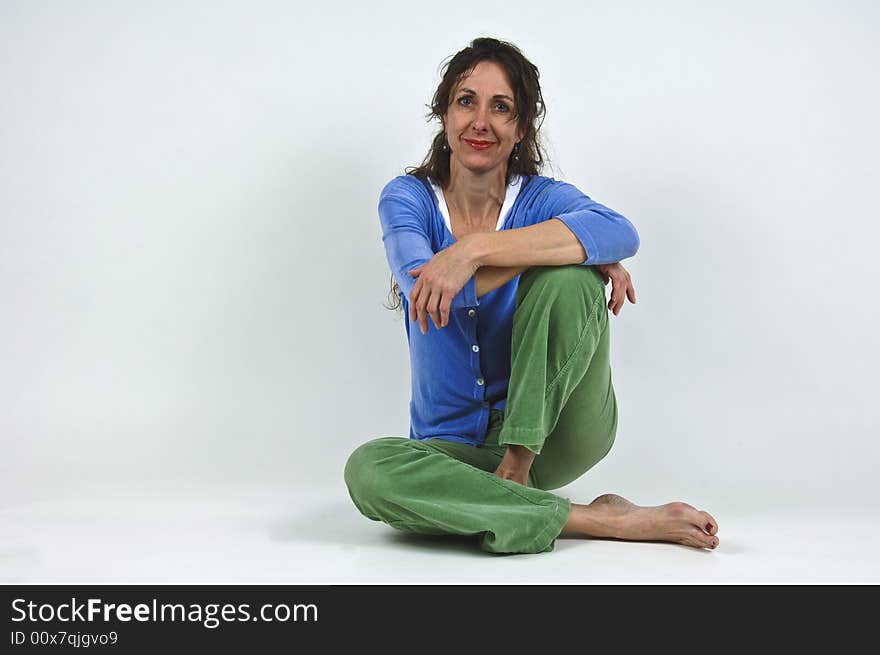 Attractive middle-aged caucasian woman with long brown hair, sitting cross-legged on floor. Attractive middle-aged caucasian woman with long brown hair, sitting cross-legged on floor.