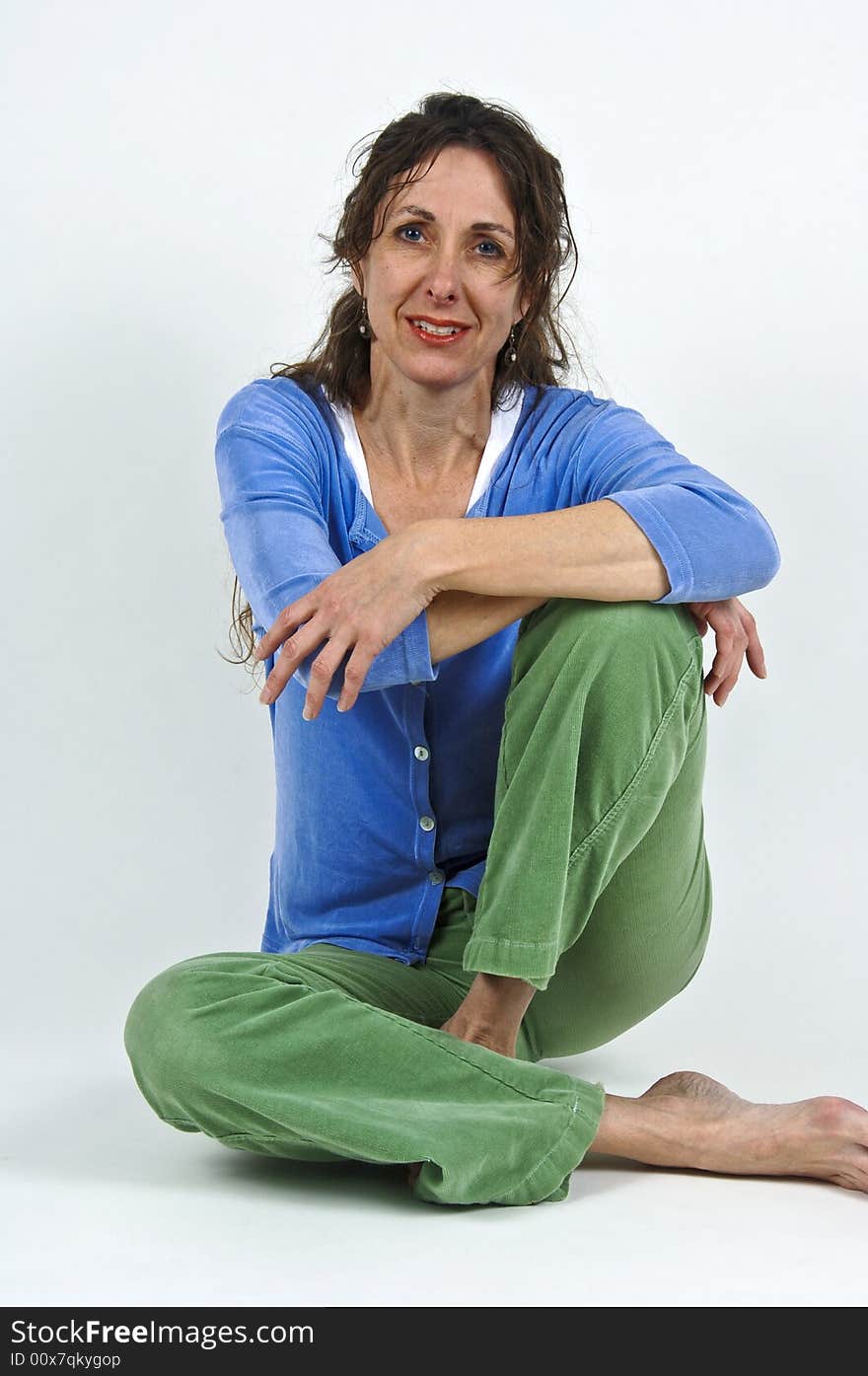 Attractive middle-aged caucasian woman with long brown hair, sitting cross-legged on floor. Attractive middle-aged caucasian woman with long brown hair, sitting cross-legged on floor.