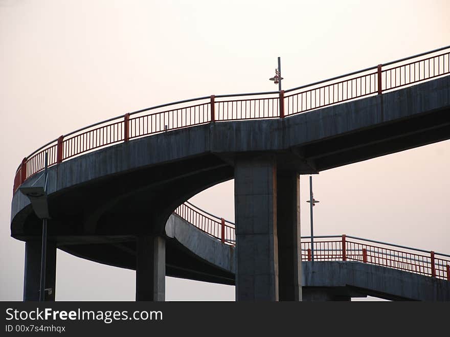 The curving footbridge with railings and street lamps tuning upward. The curving footbridge with railings and street lamps tuning upward.