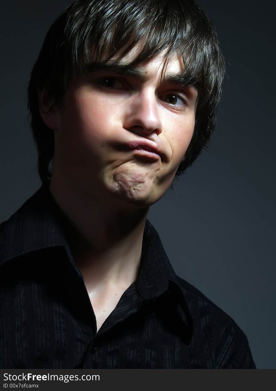 A portrait about a trendy cute young guy who is looking towards and he is pulling faces. He is wearing a stylish black shirt. A portrait about a trendy cute young guy who is looking towards and he is pulling faces. He is wearing a stylish black shirt.