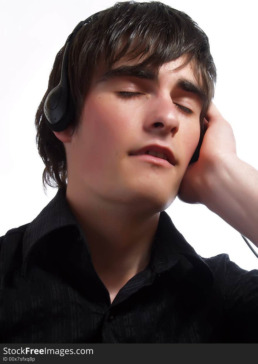 A portrait about a trendy handsome young guy who is smiling, he is listening to music and he is feeling the pleasure of it. He is wearing a stylish black shirt. A portrait about a trendy handsome young guy who is smiling, he is listening to music and he is feeling the pleasure of it. He is wearing a stylish black shirt.