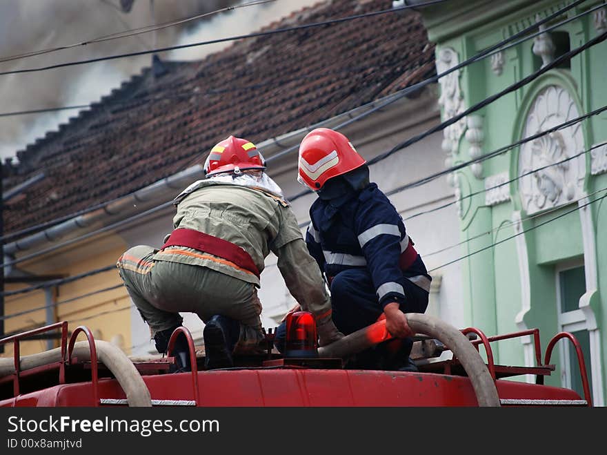 Two firemen in action on the roof of a fire truck. Two firemen in action on the roof of a fire truck