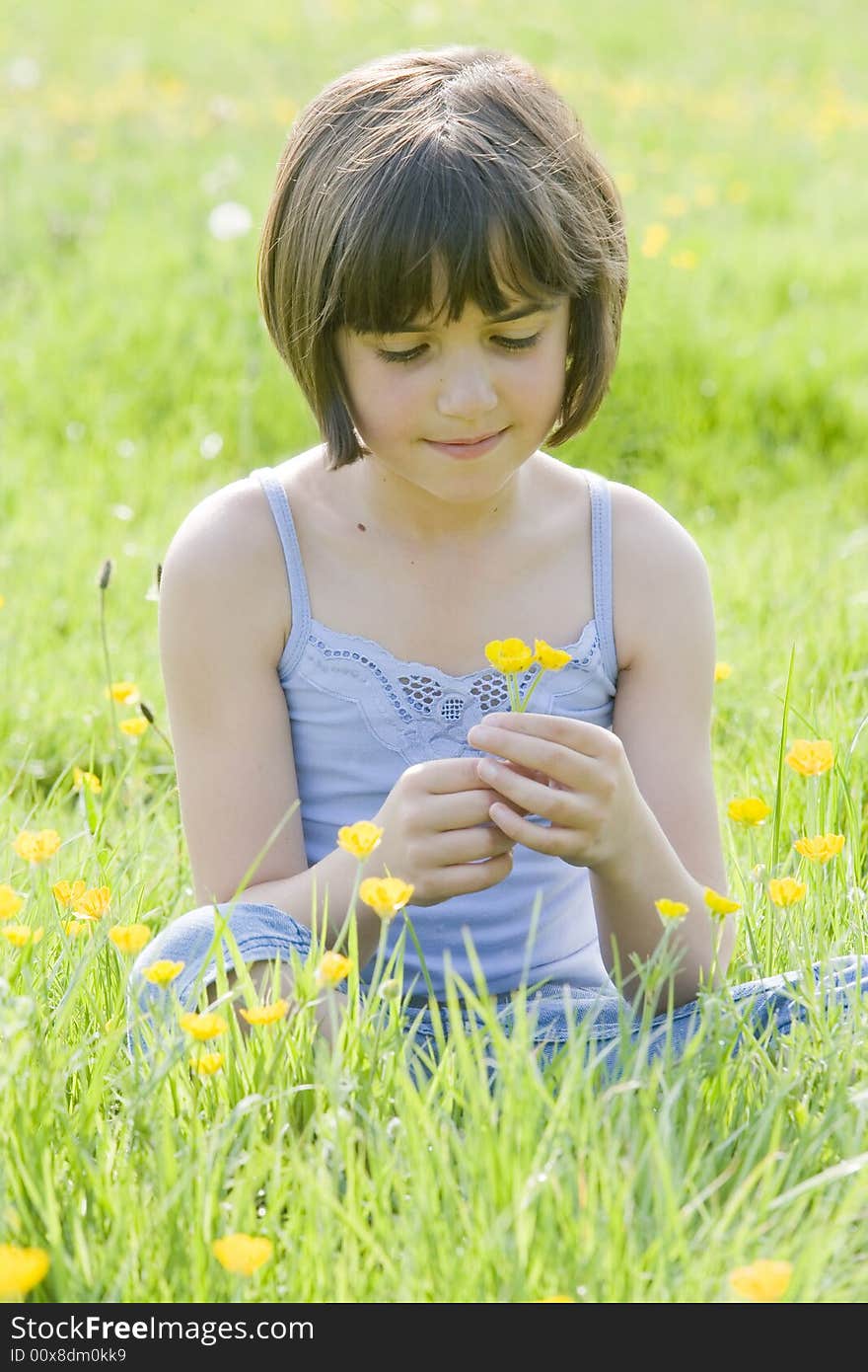 Young female child sitting cross legged in a field full of buttercups. Young female child sitting cross legged in a field full of buttercups