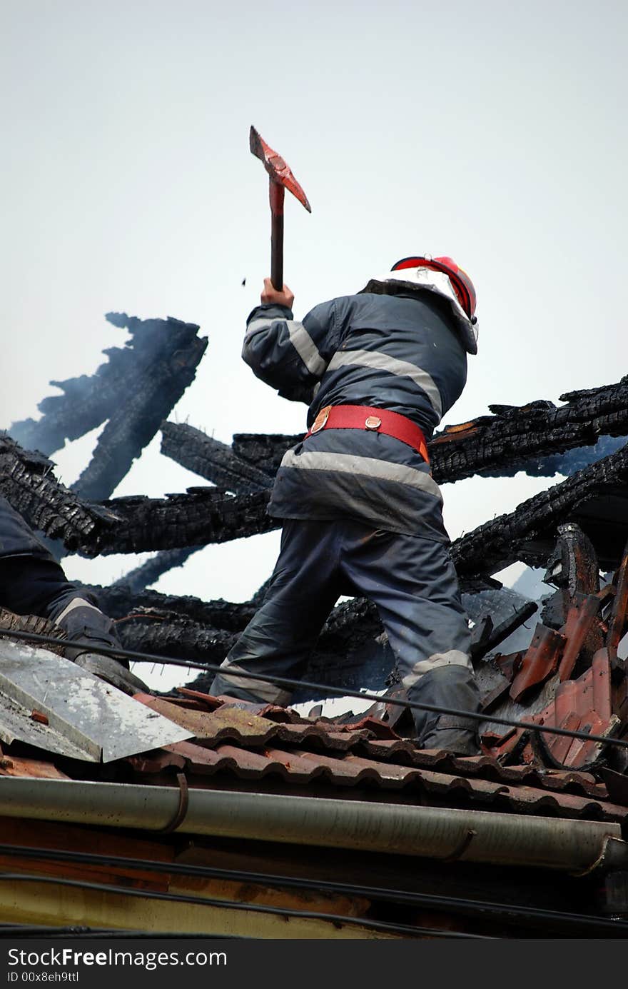 Fireman in action on the roof of a burning house