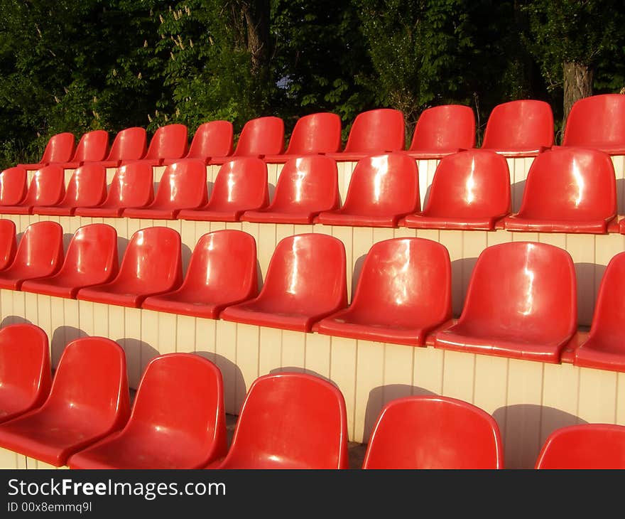 Red chairs situated in raw's on stadium