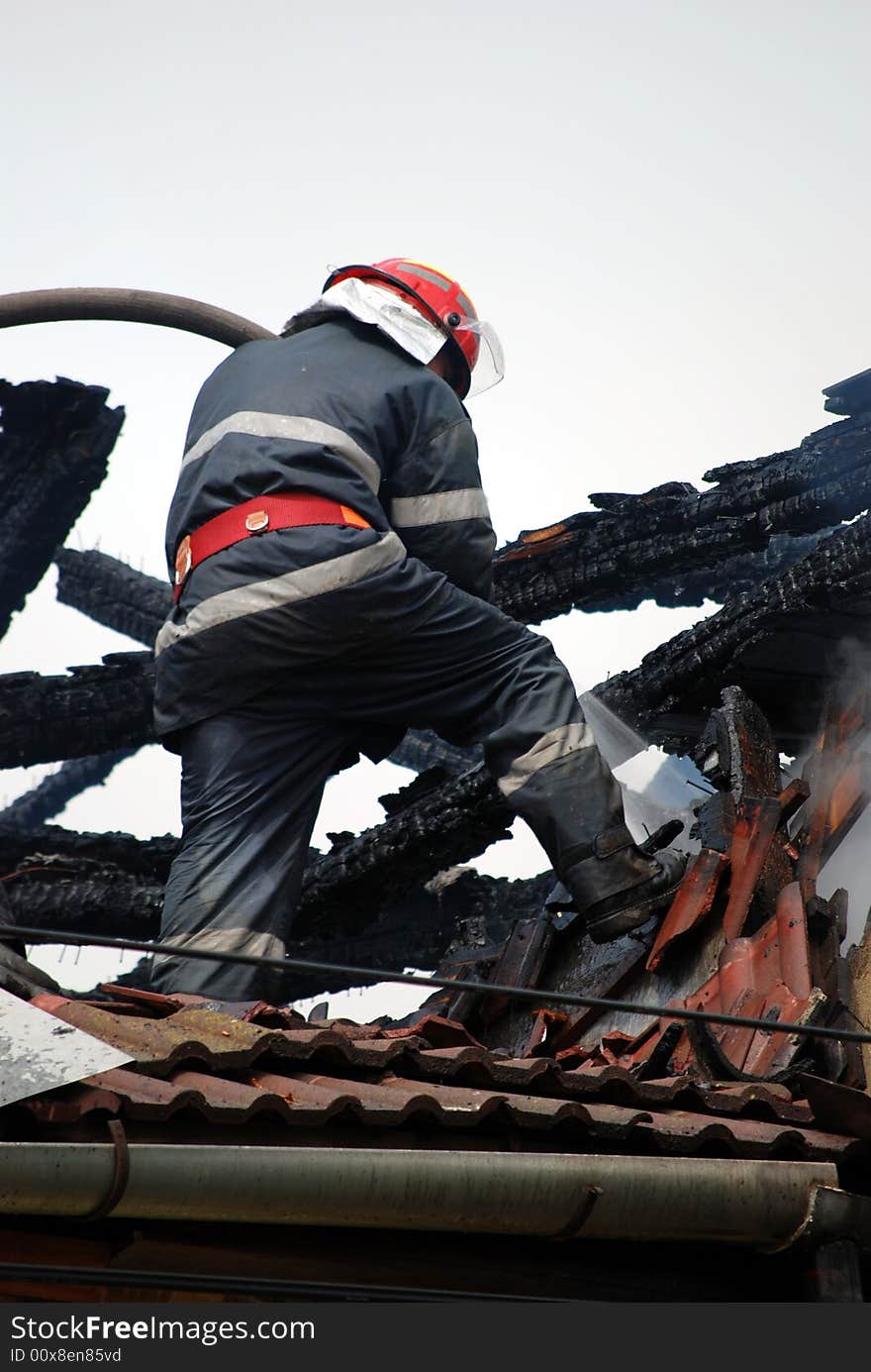 Fireman in action on the roof of a burning house