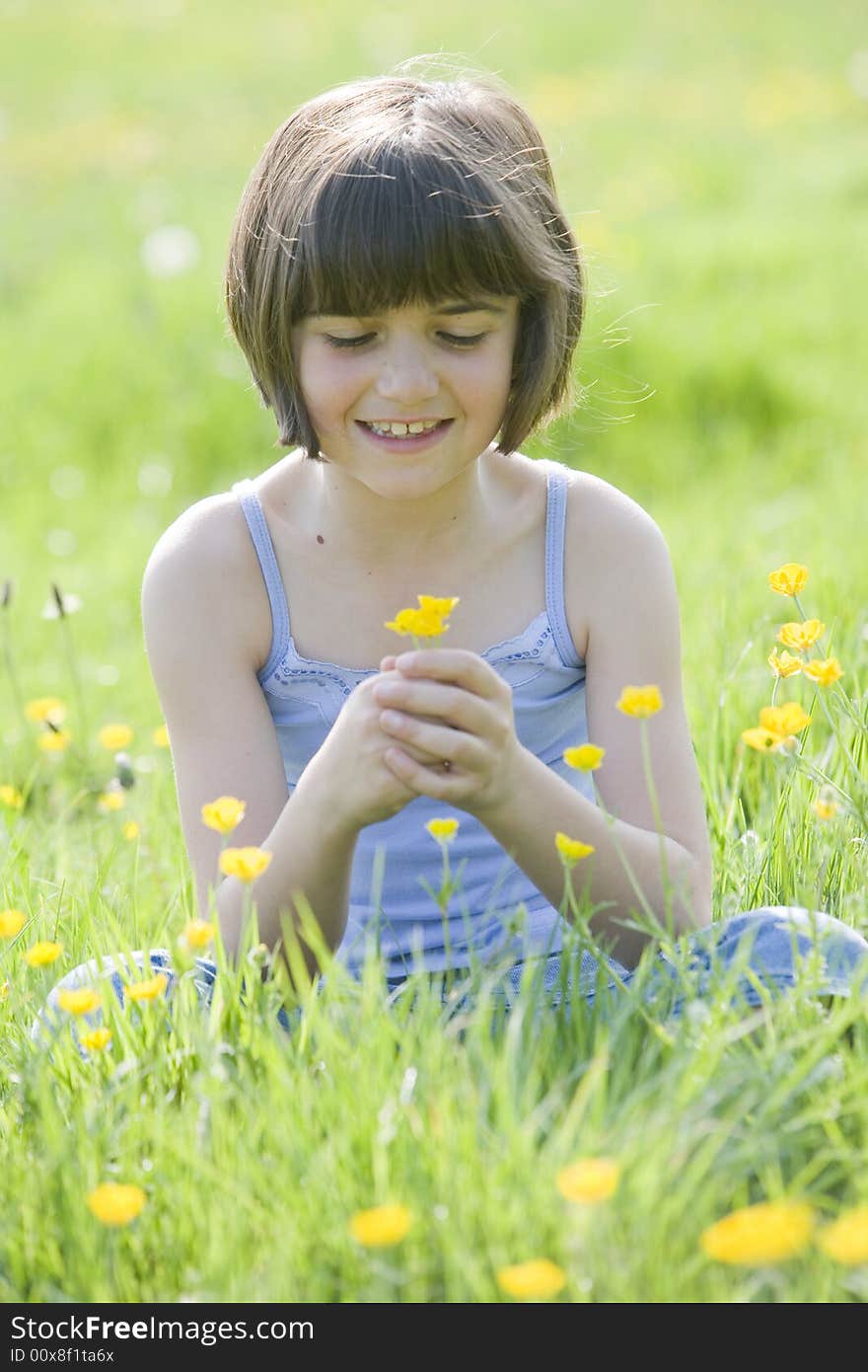 Young female child sitting cross legged in a field full of buttercups smiling. Young female child sitting cross legged in a field full of buttercups smiling