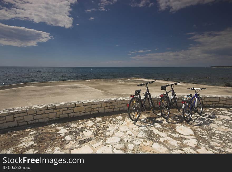 Three bicycles parked at the edge of a sea