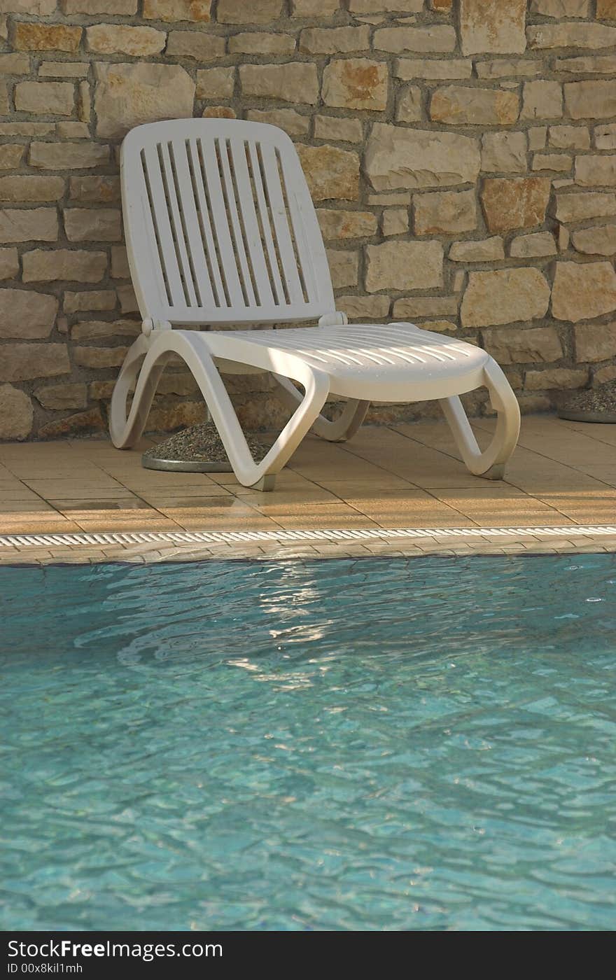 White plastic seats standing on a terrace next to a pool