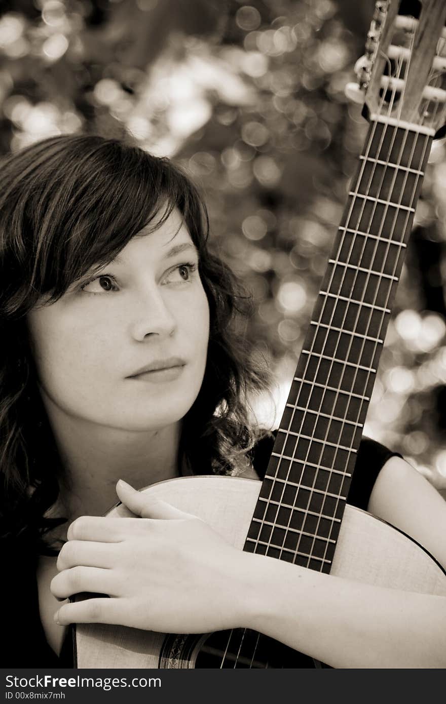 Young woman holding her classic guitar, sepia toned. Young woman holding her classic guitar, sepia toned.