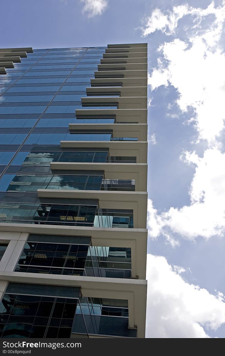 A high rise blue glass office tower rising into the clouds. A high rise blue glass office tower rising into the clouds