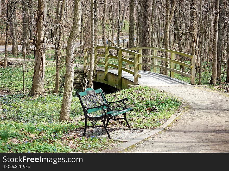 This is a park bench by a bridge. This is a park bench by a bridge