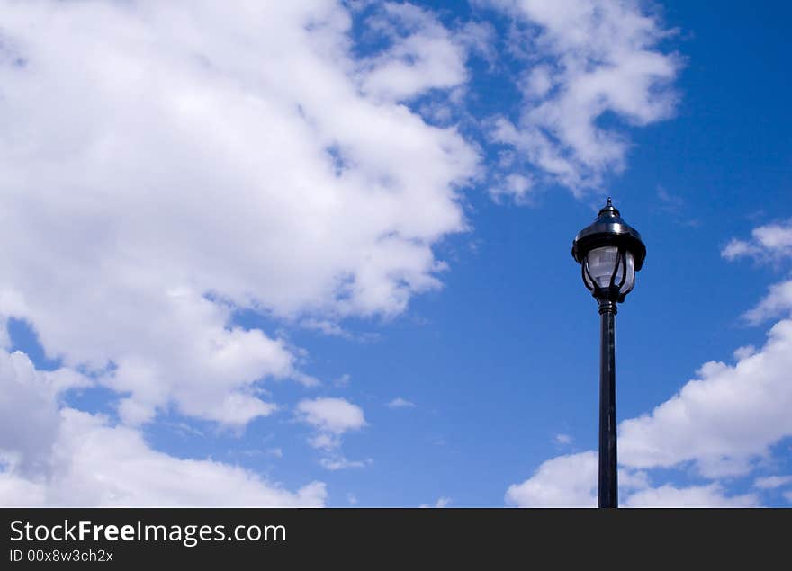 A single English style lamp with a cloudy blue sky behind. A single English style lamp with a cloudy blue sky behind.