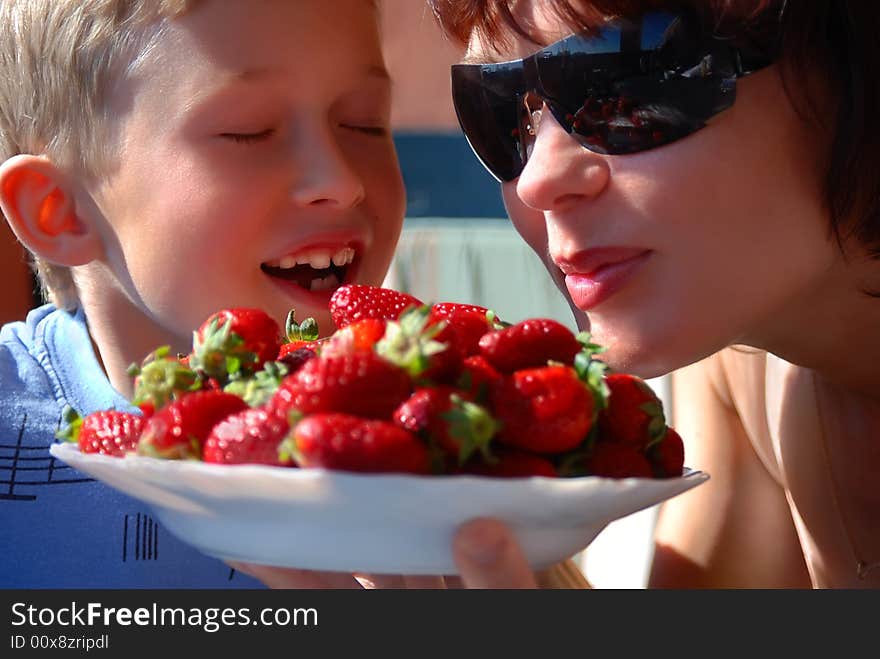 Mother and the son eat a strawberry