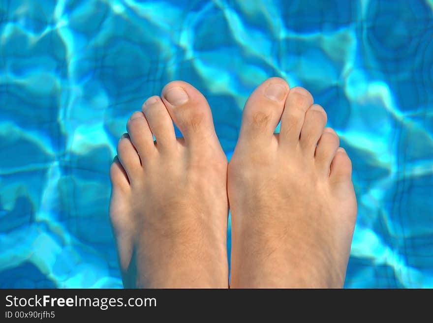 Feet in blue water on swimming pool