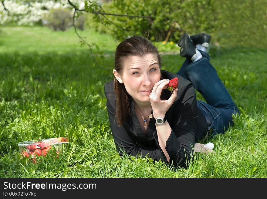 Pretty girl relaxing on green grass and eat red fresh strawberry. Pretty girl relaxing on green grass and eat red fresh strawberry