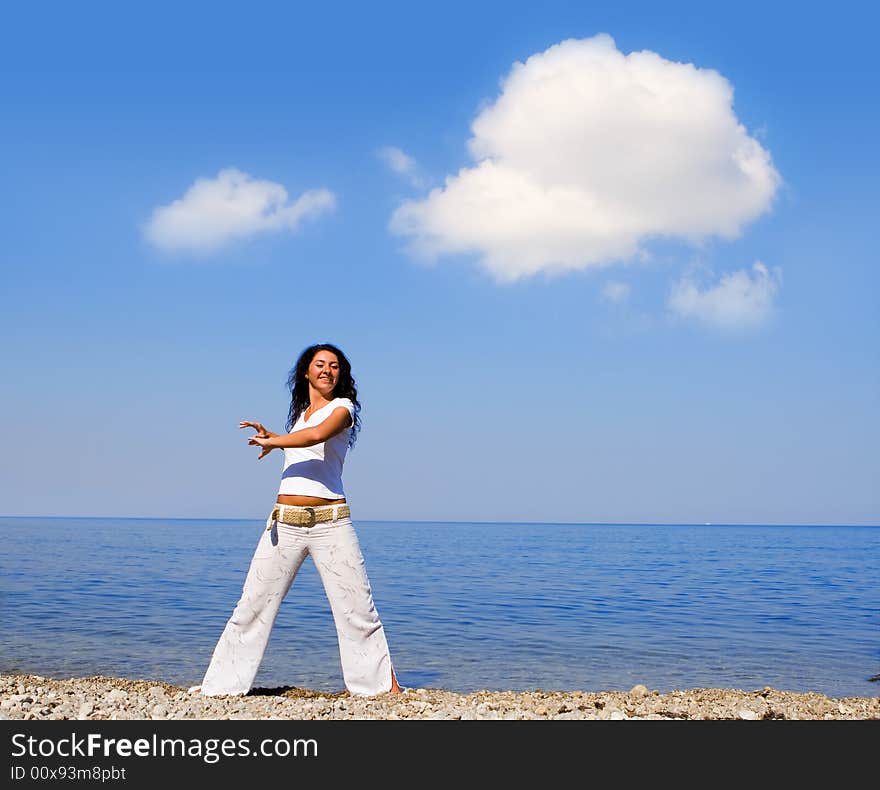 Young beautiful woman doing fitness exercises in the sea