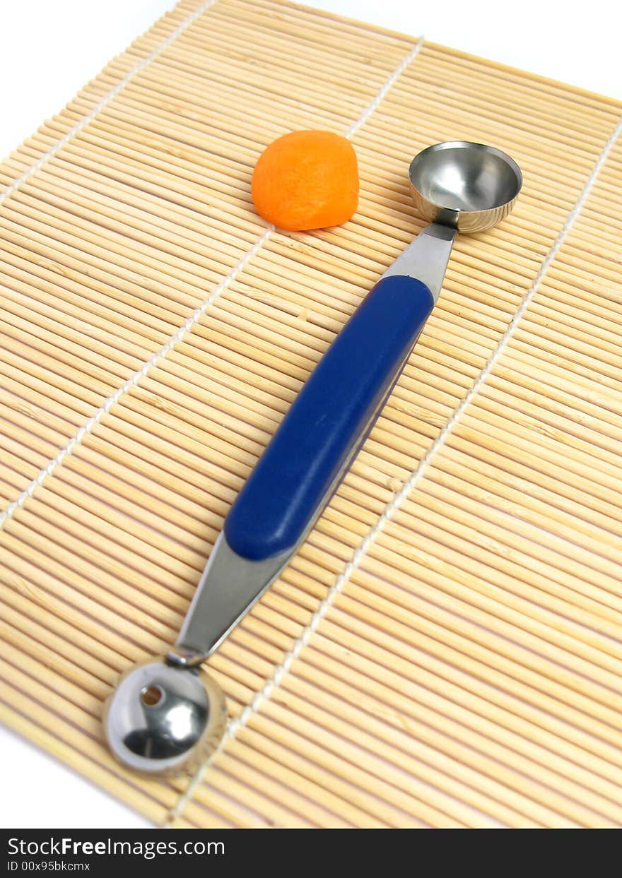 Noisette potato cutter with a rounded carrot on a bamboo mat. Noisette potato cutter with a rounded carrot on a bamboo mat