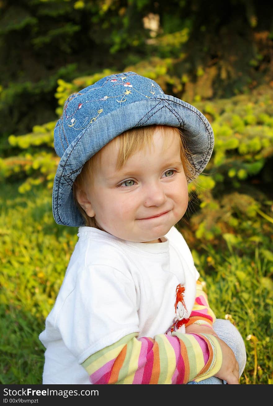 The small beautiful girl sits on a grass and smiles. The small beautiful girl sits on a grass and smiles