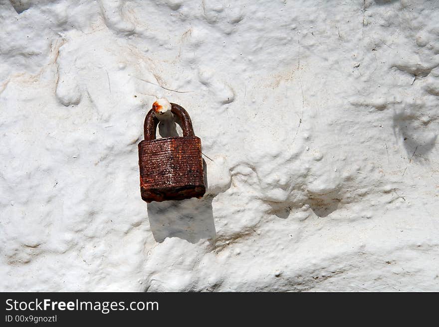 Rusty red padlock on old dirty white wall