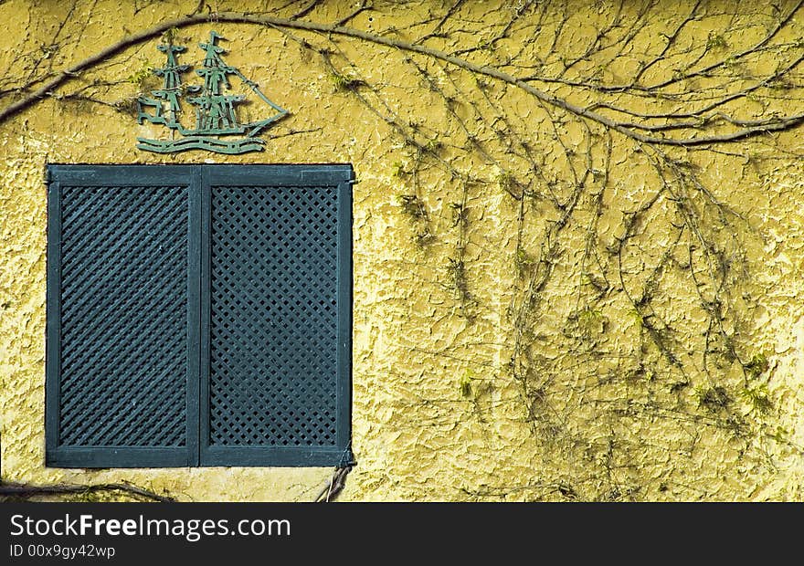 Antique blue window against yellow wall in Spain, seen near LLoret (jardins de santa clotylda)