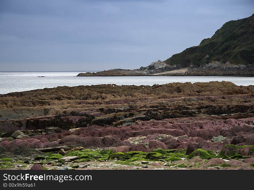 Sunshine sea view with overcast sky, low-tide beach, Cornwell, England