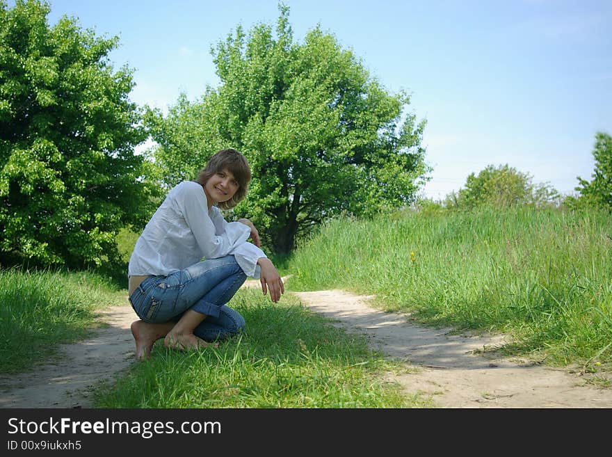 A young attractive woman sitting in a path on a warm summer day