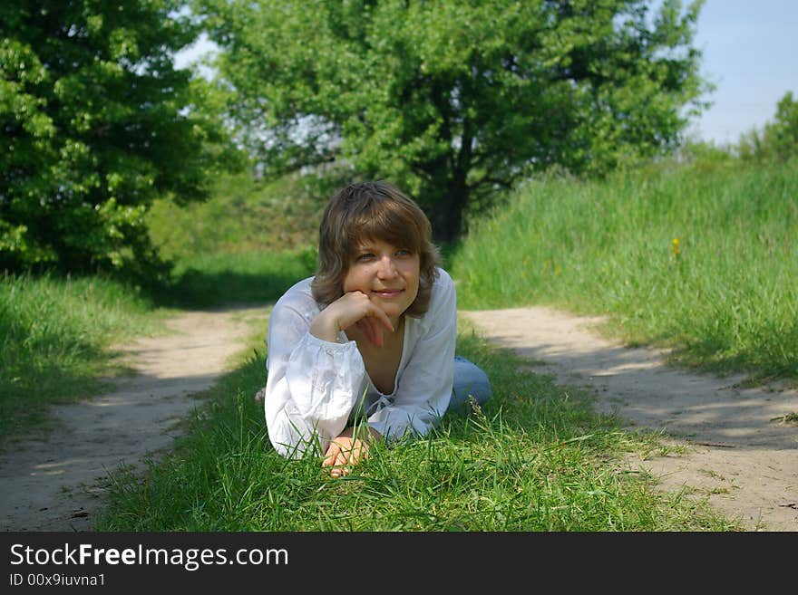 A young attractive woman sitting in a path on a warm summer day