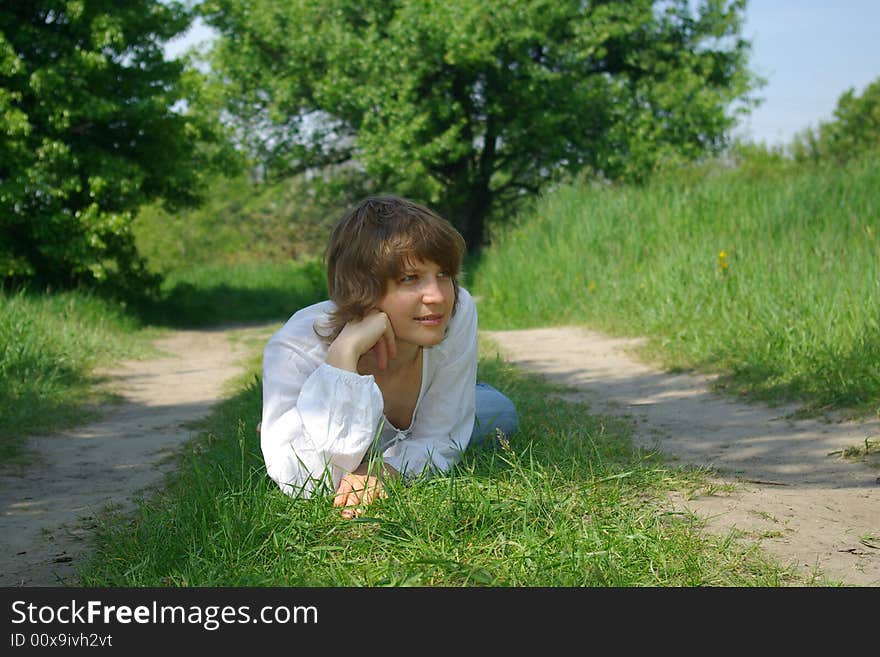 A young attractive woman sitting in a path on a warm summer day