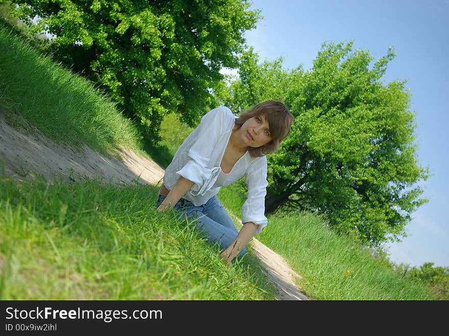 A young attractive woman sitting in a path on a warm summer day